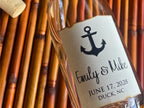 Glass bottle with a personalized label featuring an anchor design, text, and cork on a bamboo background.