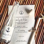 Nautical-themed wedding invitation with bottle and cork on a woven surface