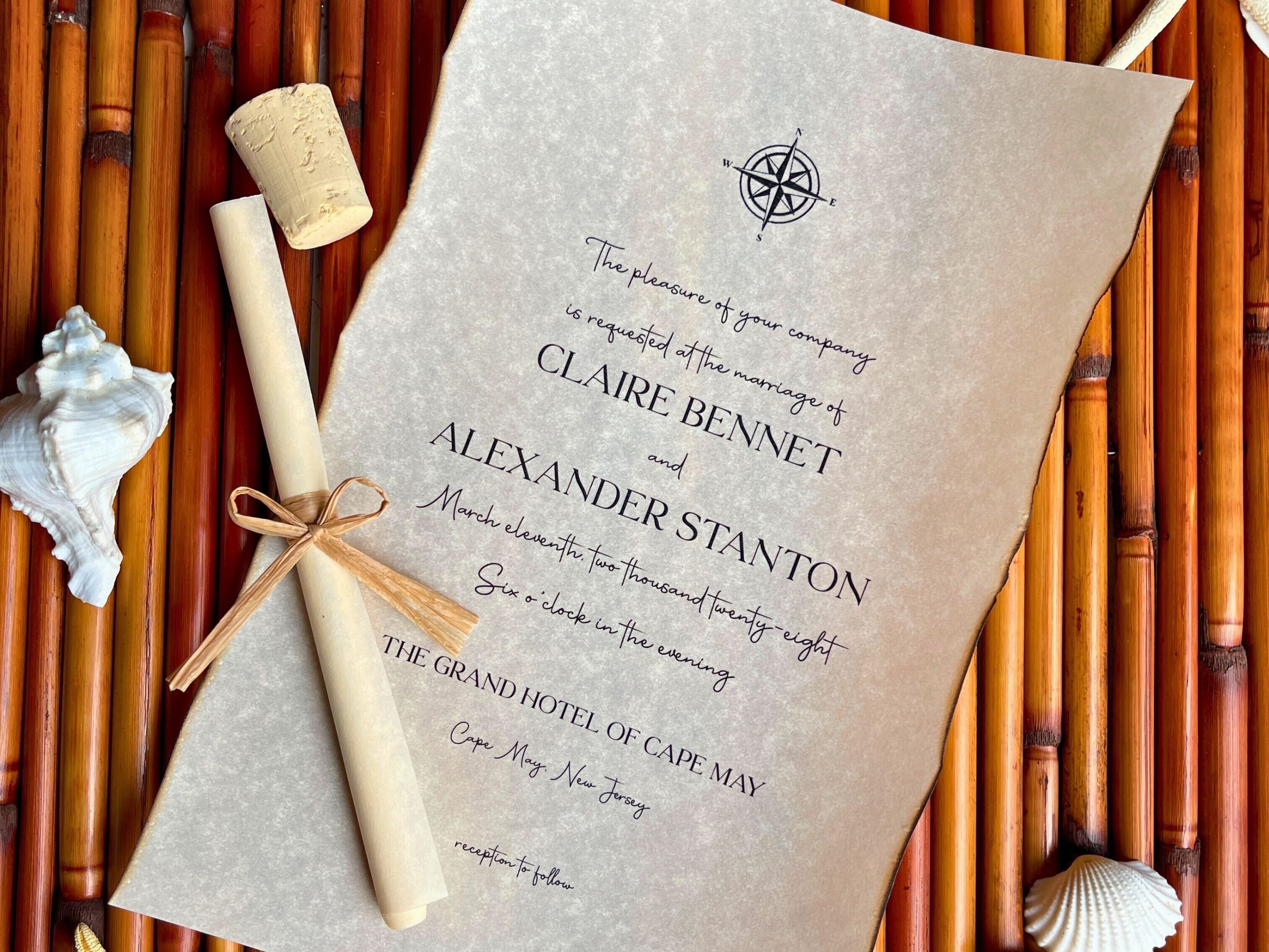 Wedding invitation with scroll and compass design on vellum paper against a bamboo background