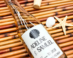 Glass bottle with a label on a woven surface with a shell and starfish.