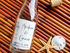Glass bottle with personalized lighthouse theme label on a woven mat with a starfish and sand dollar.