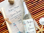 Personalized glass bottle label with lighthouse design and wedding invitation on textured paper.