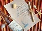 Personalized wedding invitation with bottle, cork, and nautical elements on a woven surface