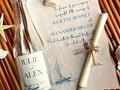 Nautical-themed wedding invitation with a glass bottle.