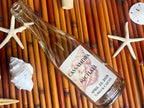 Personalized bottle with a shell design label on a bamboo mat with starfish and shells.