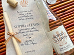 Glass bottle with personalized label and wedding invitation on a textured surface