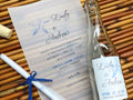 Wedding invitation with starfish design on a woven mat with a bottle and cork.