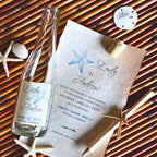 Wedding invitation with bottle and starfish elements on a woven background