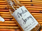 Glass bottle with a personalized label on a woven surface