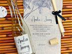 Wedding invitation with bottle and cork on a woven surface