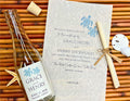 Glass bottle with turtle label and wedding invitation on a woven surface