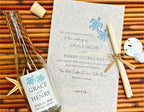 Glass bottle with turtle label and wedding invitation on a woven surface