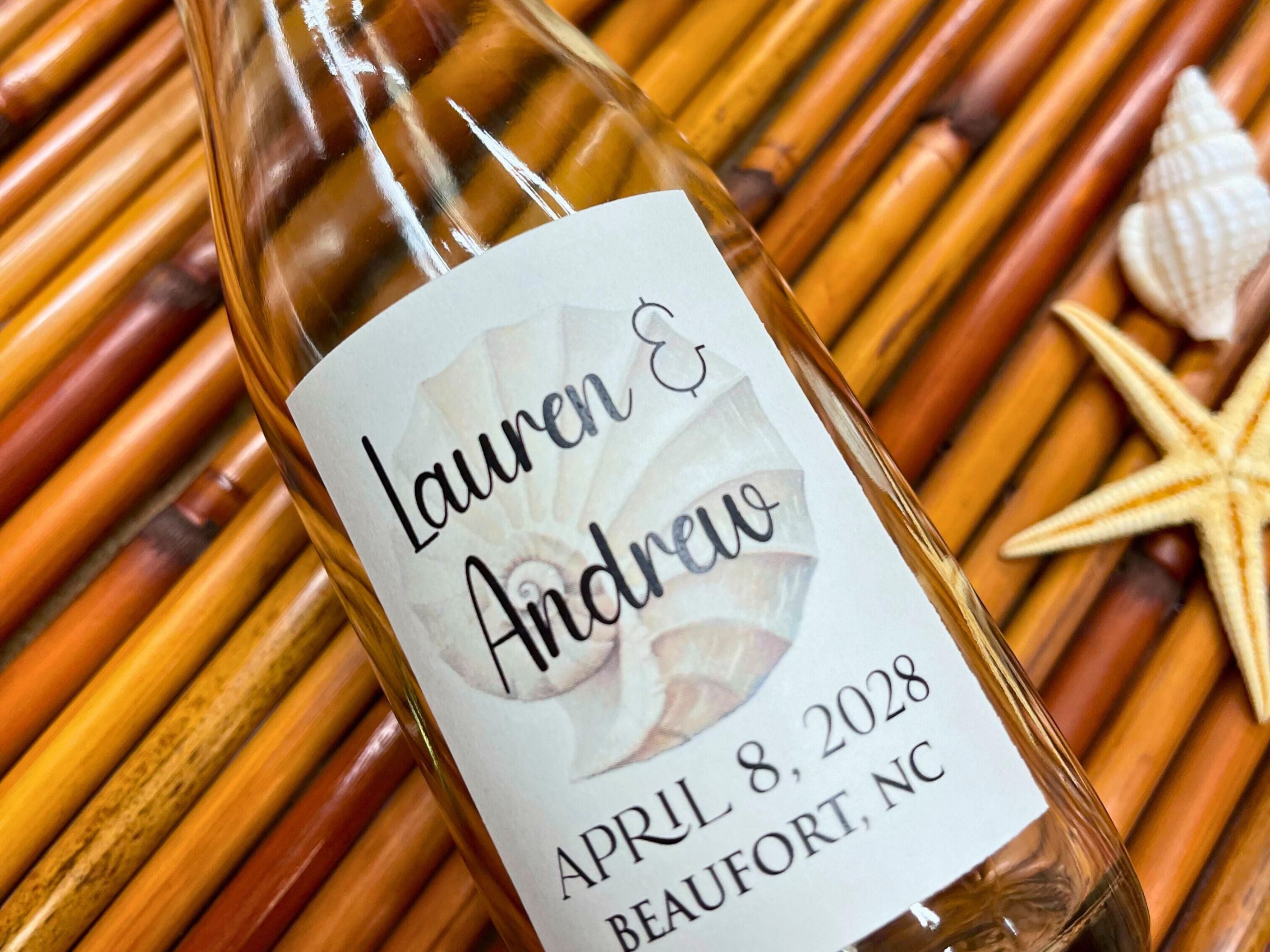 Glass bottle with a personalized label on a woven surface with starfish and shells.
