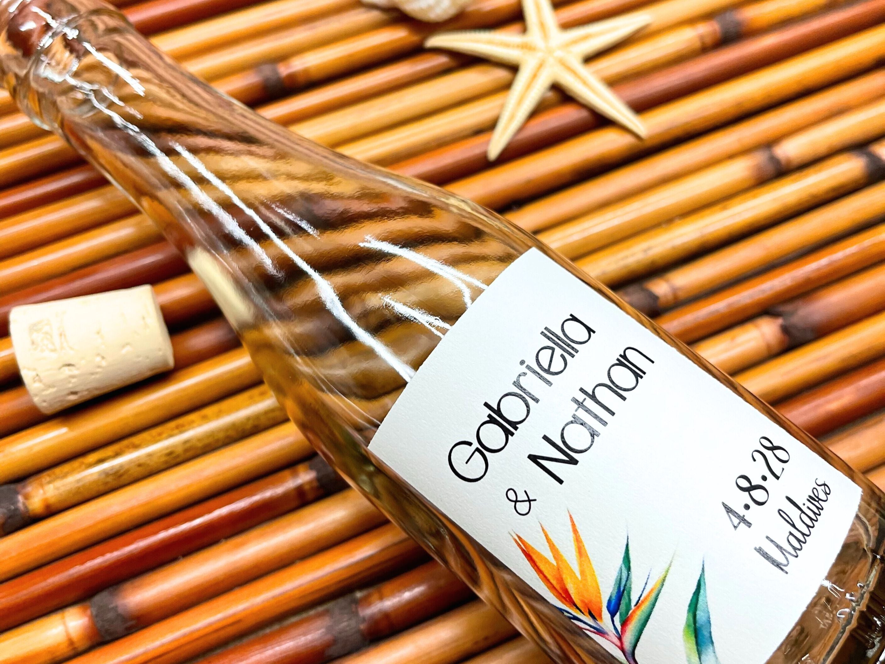 Glass bottle with a personalized label for an event in the Maldives on bamboo surface