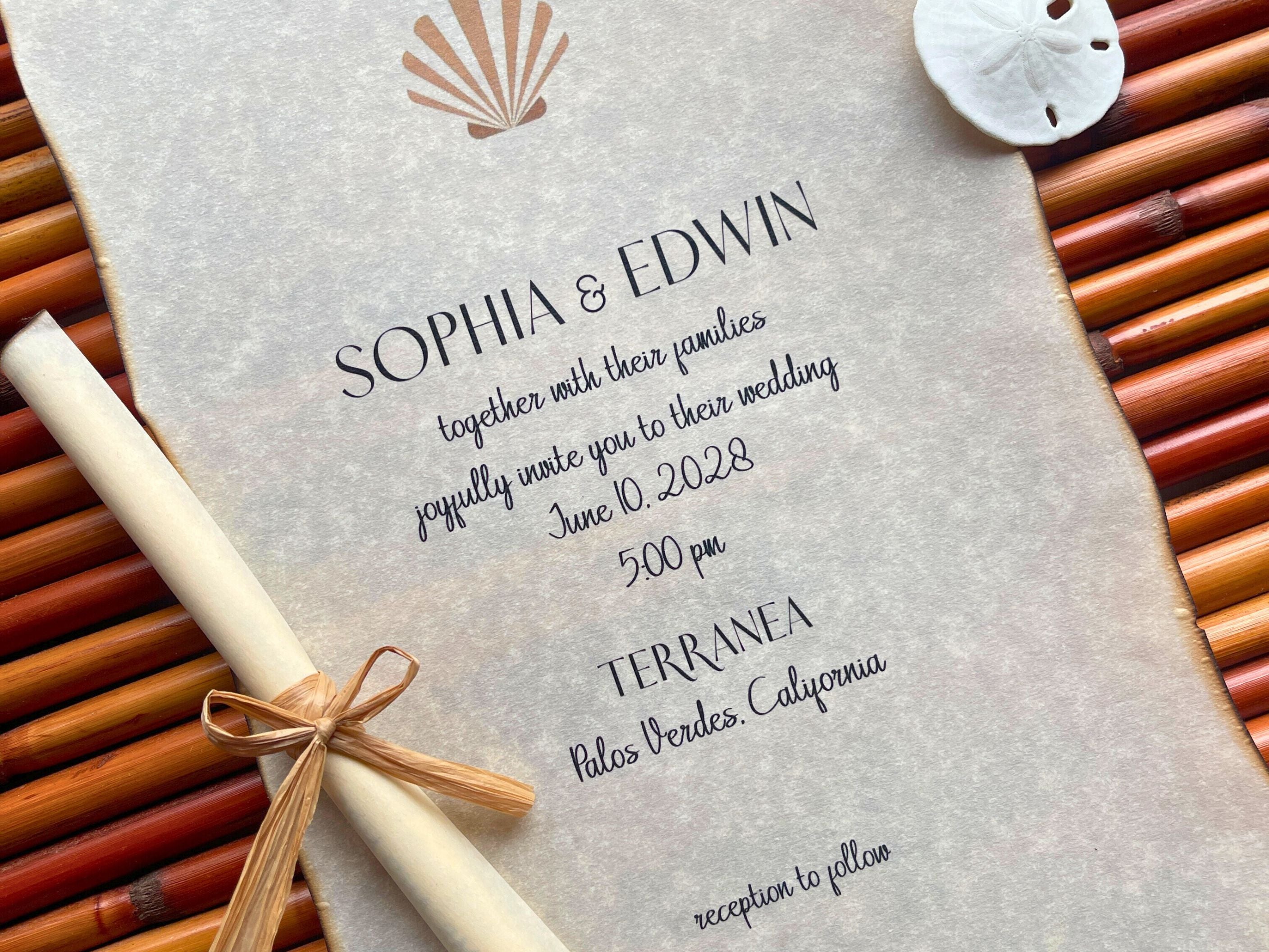 Vellum Wedding invitation with shell design and rolled-up paper scroll on textured surface