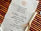 Wedding invitation with shell design and hand-burnt edges on a textured surface