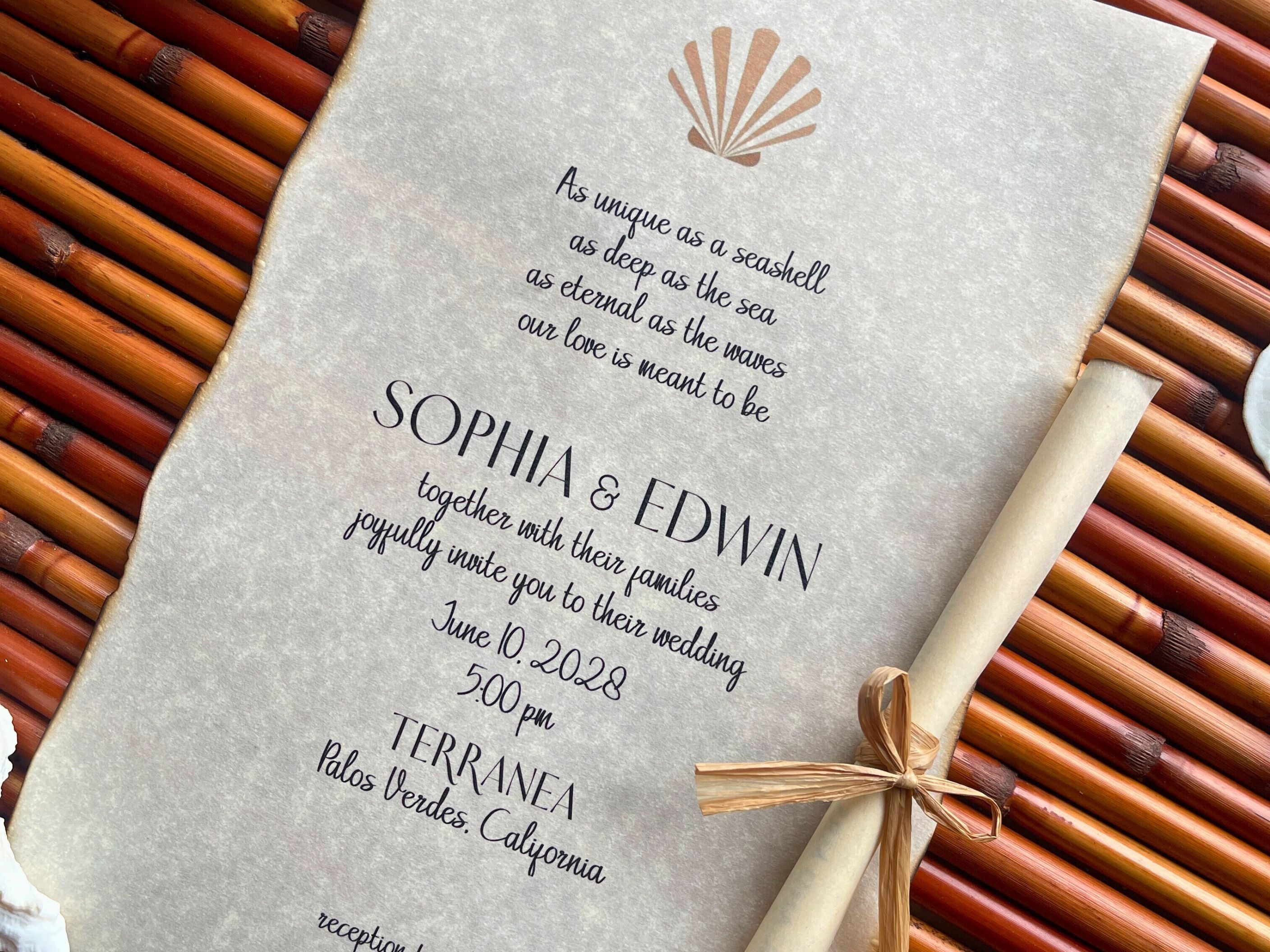 Wedding invitation with shell design and hand-burnt edges on a textured surface